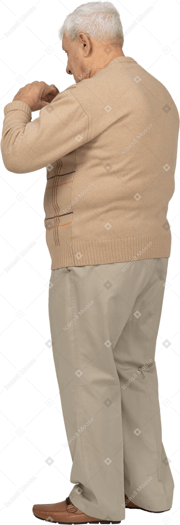 Vista lateral de un anciano con ropa informal haciendo corazón con los dedos