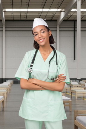 A woman in scrubs and a stethoscope standing with her arms crossed