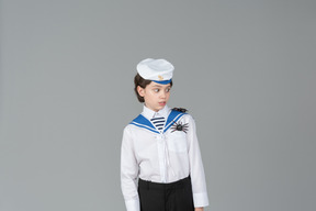 Niño en uniforme de marinero asustado de arañas en sus hombros.