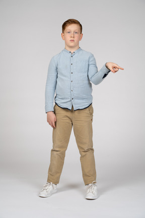 Vista frontal de um menino apontando com o dedo e olhando para a câmera