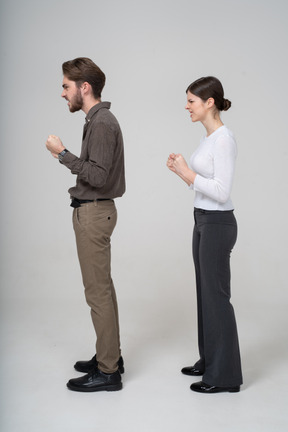 Side view of a furious couple in office clothing clenching fists