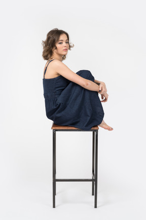 Fille sérieuse assise sur un tabouret de bar profondément dans ses pensées