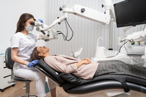 Full-length of a female dentist examining her female patient and looking through the microscope