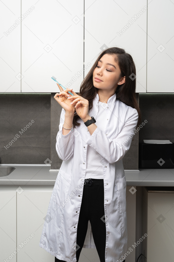 Front view of a female dentist looking attentively at the toothbrush