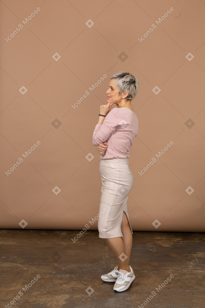 Вдумчивая женщина в повседневной одежде стоит в профиль