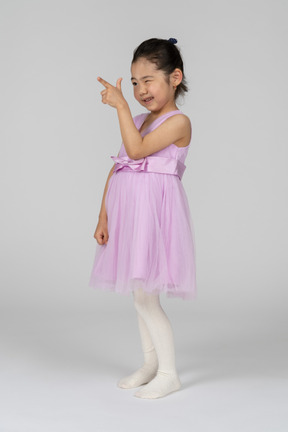 Little girl in pink dress pointing with a finger gun