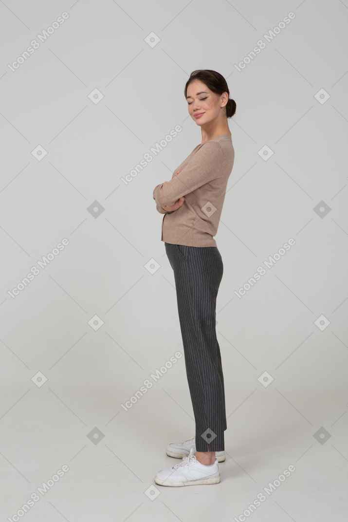 Side view of a bossy young lady in beige pullover crossing hands