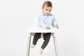 Adorable bebé niño sentado en una silla alta