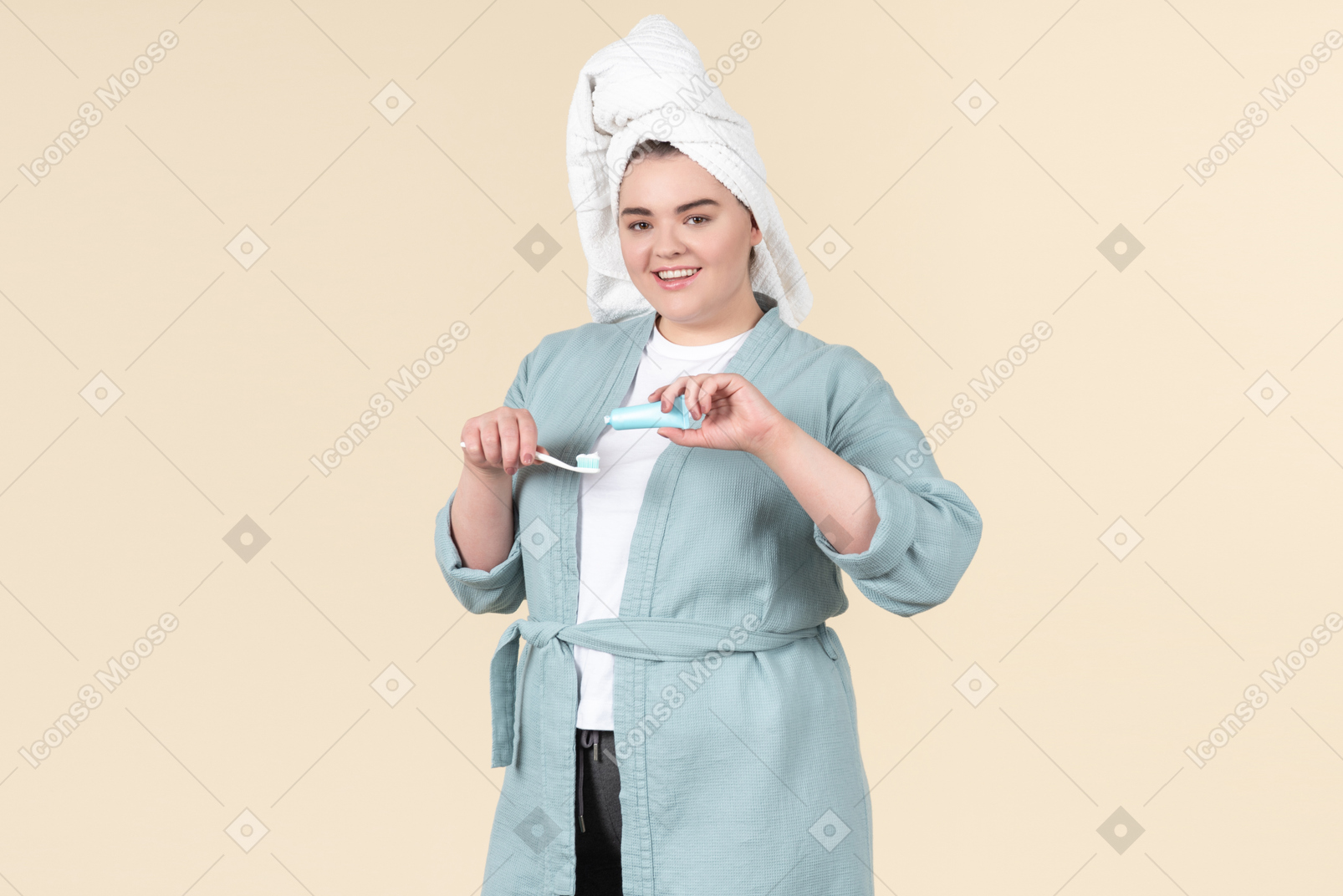 Young plus-size girl in a blue bathrobe brushing her teeth after a shower