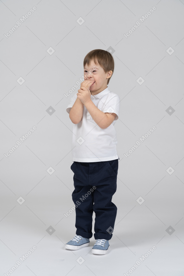 Smiling little boy biting his hand