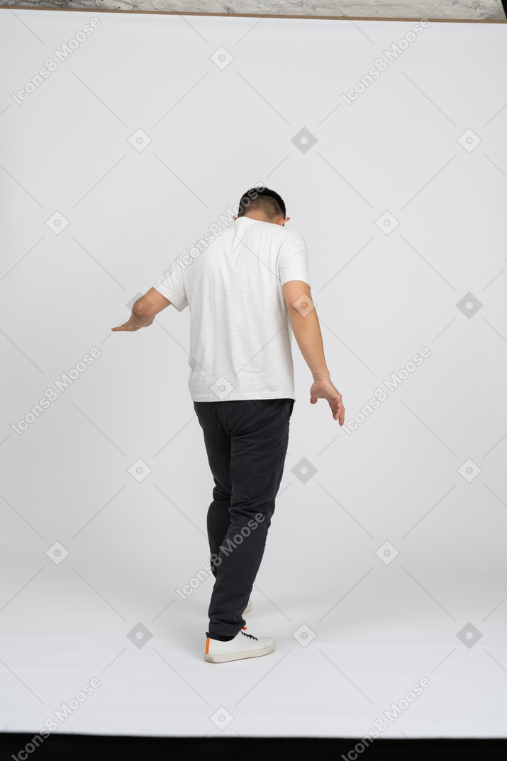 一个穿着休闲服的男人张开双臂走路的后视图