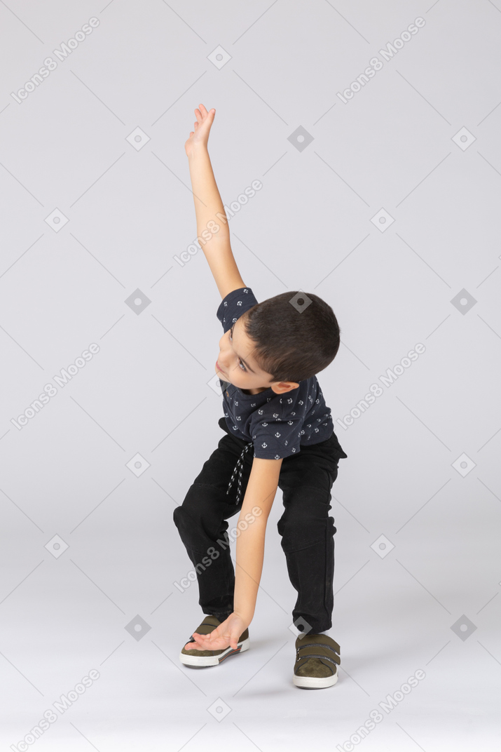Front view of a cute boy touching floor with hand