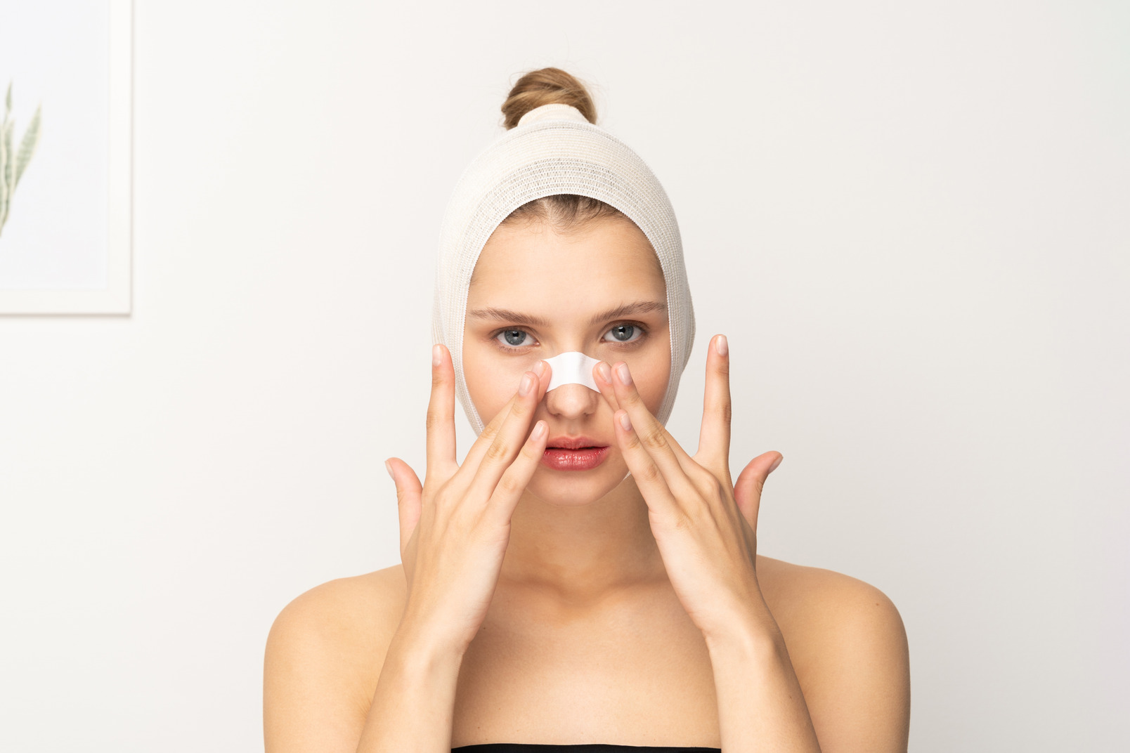 Woman with head bandage placing plaster on her nose