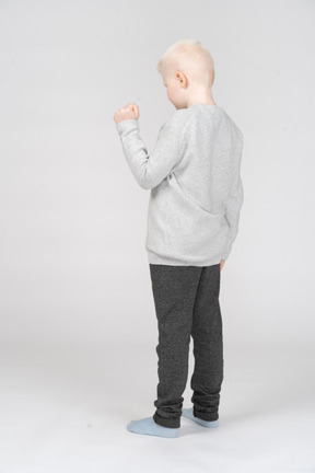 Little boy standing with his fist raised