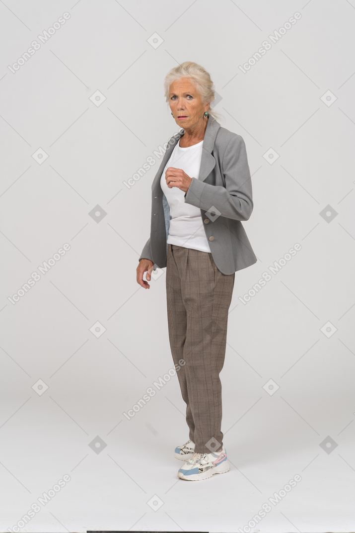 Vue de face d'une vieille dame impressionnée en costume regardant la caméra