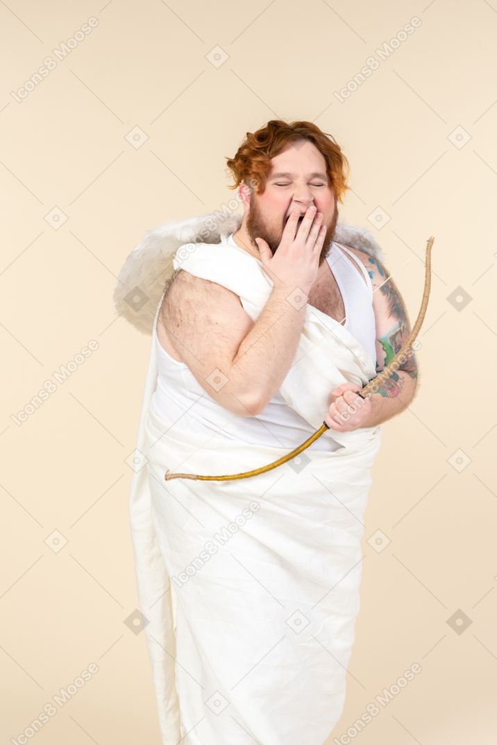 Big guy dressed as a cupid holding bow and yawning