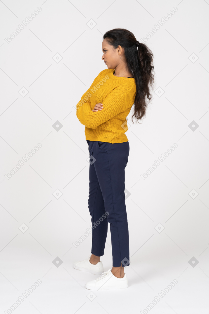 Side view of a girl in casual clothes posing with crossed arms and making faces