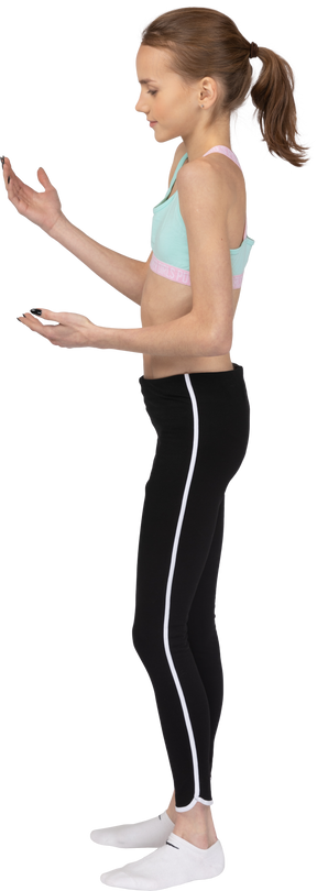 Vista lateral de uma adolescente em roupas esportivas levantando as mãos