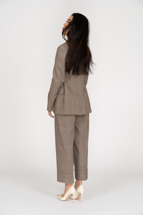 背を向ける茶色のビジネススーツを着た若い女性の4分の3の背面図