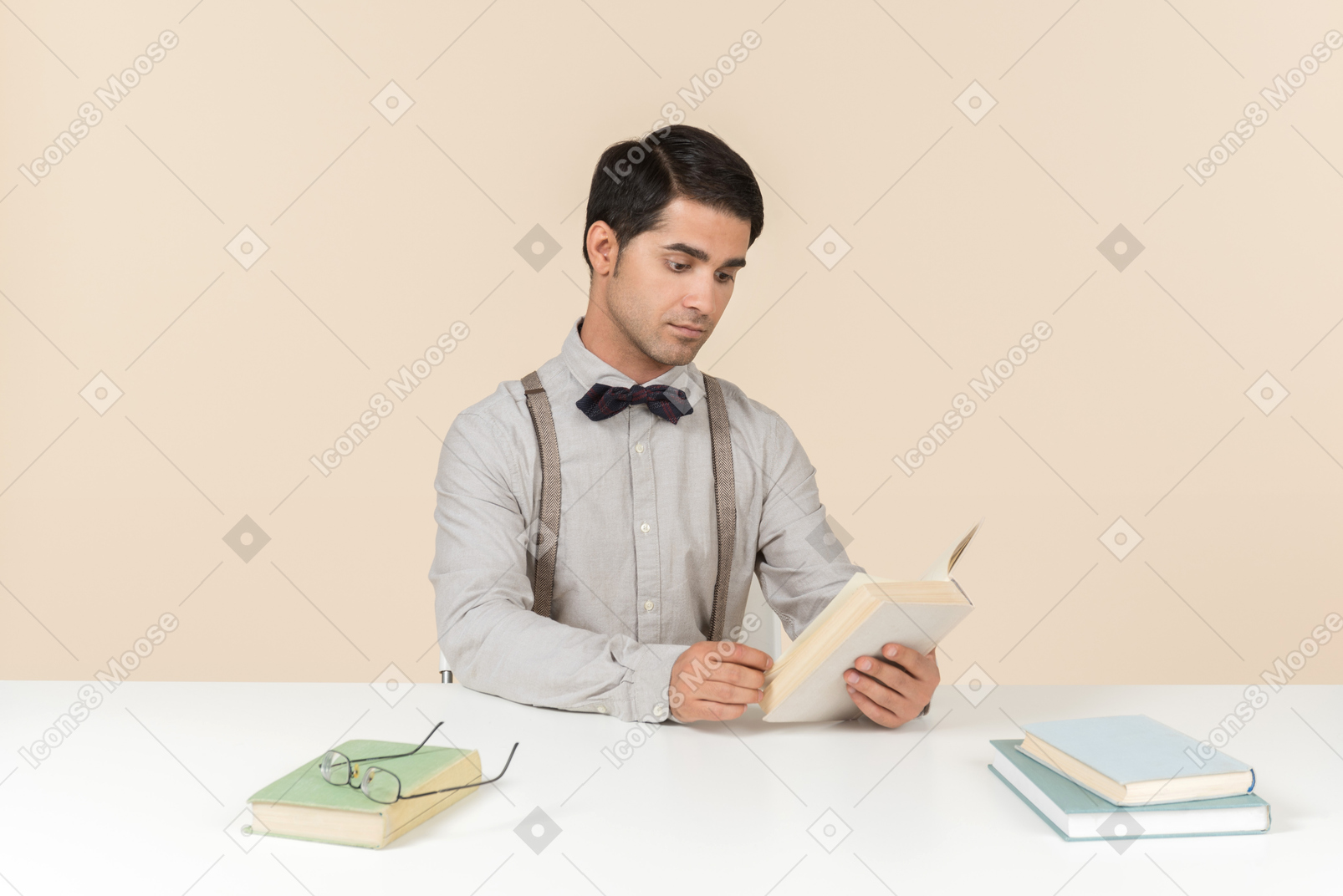 Jovem professor sentado à mesa e ler um livro