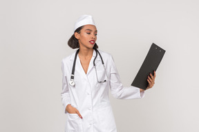 Atraente médico feminino olhando através de alguns documentos