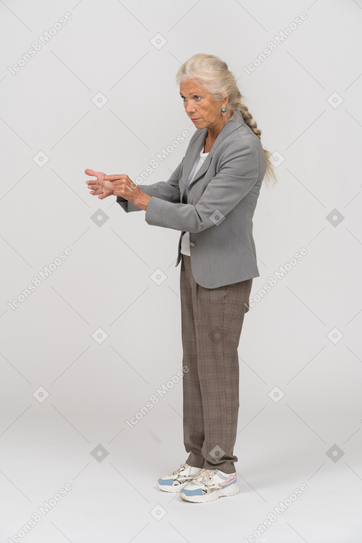 Вид сбоку на серьезную старушку в костюме, которая что-то объясняет