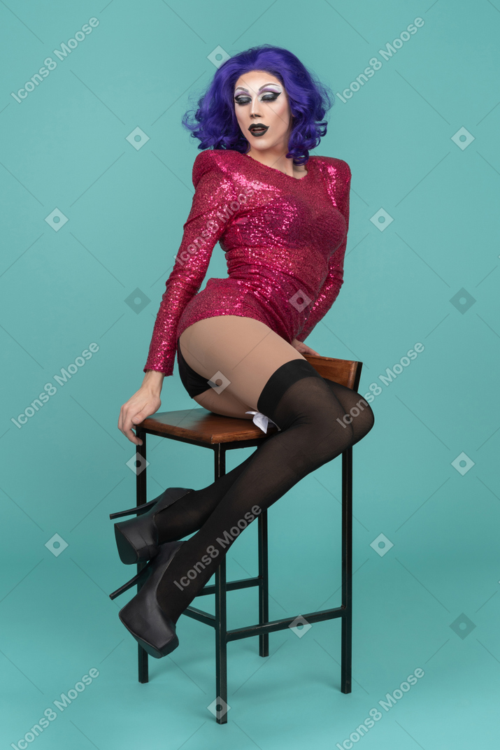 Drag queen lifting hips halfway off the seat & posing seductively