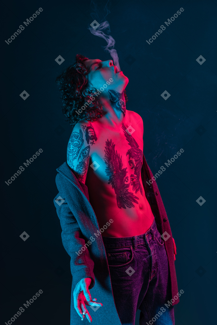 Young tattooed male taking off his jacket and smoking