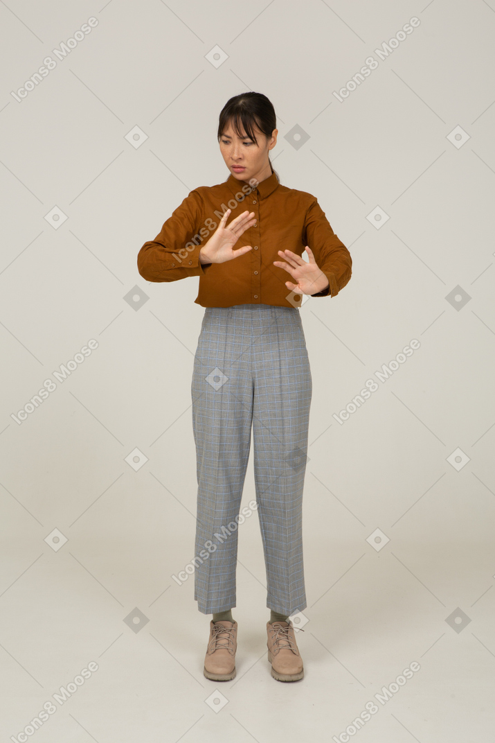 Vue de face d'une jeune femme asiatique en culotte et chemisier étendant ses bras