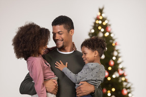 Glücklicher vater mit seinen kindern nahe einem weihnachtsbaum