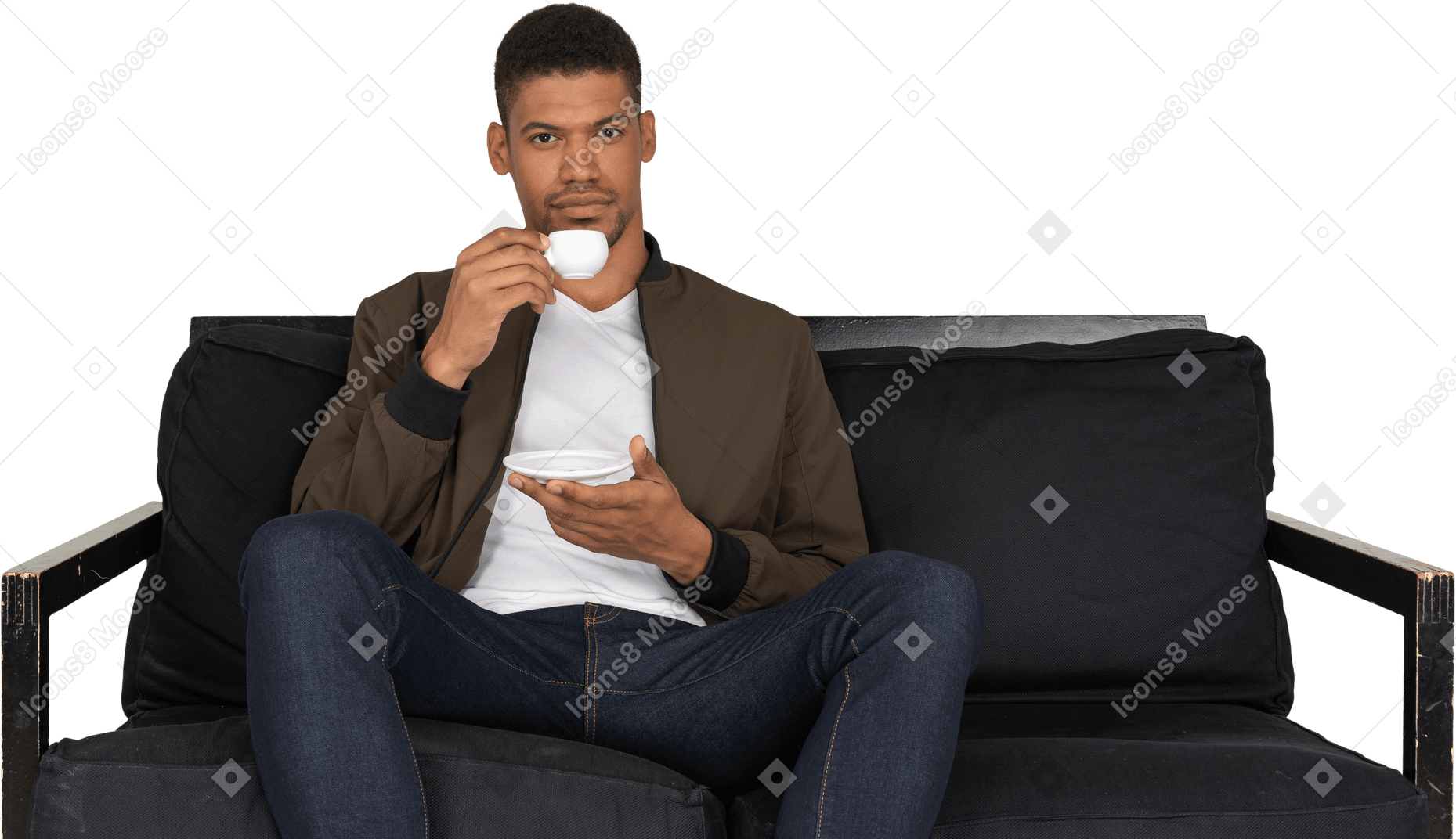 Front view of a young dreaming man sitting on a sofa while drinking coffee