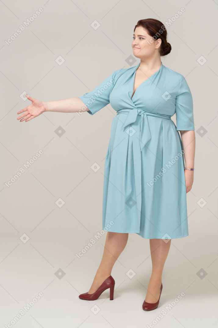 Вид спереди женщины в синем платье, протягивающей руку для пожатия