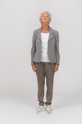 Vista frontal de una anciana en traje mirando hacia arriba
