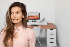 A woman standing in front of a desk with a computer on it