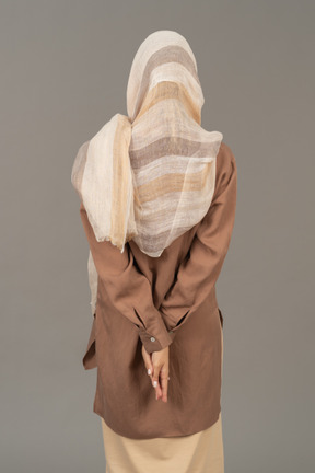 Back view of a woman folding hands behind the back