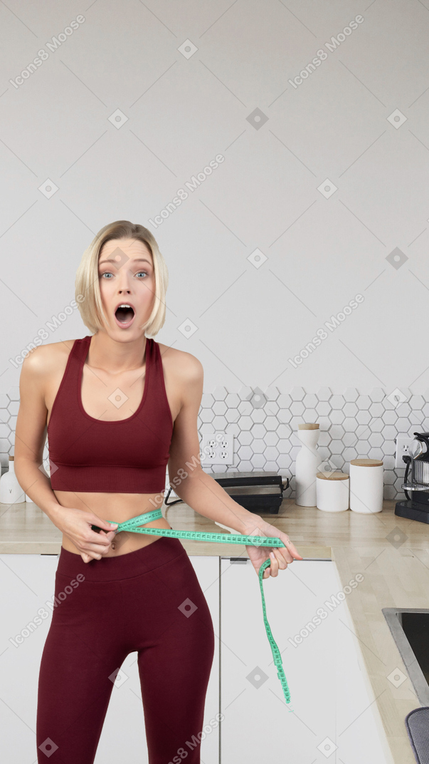 A woman holding a measuring tape in a kitchen