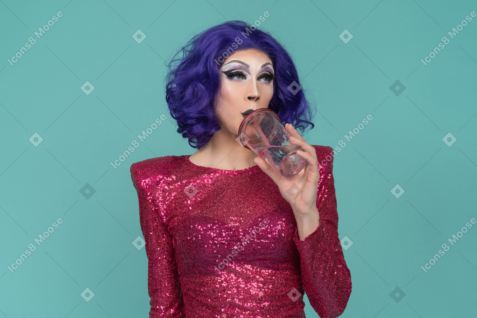 Drag queen em vestido de lantejoulas rosa tomando uma bebida do copo de plástico