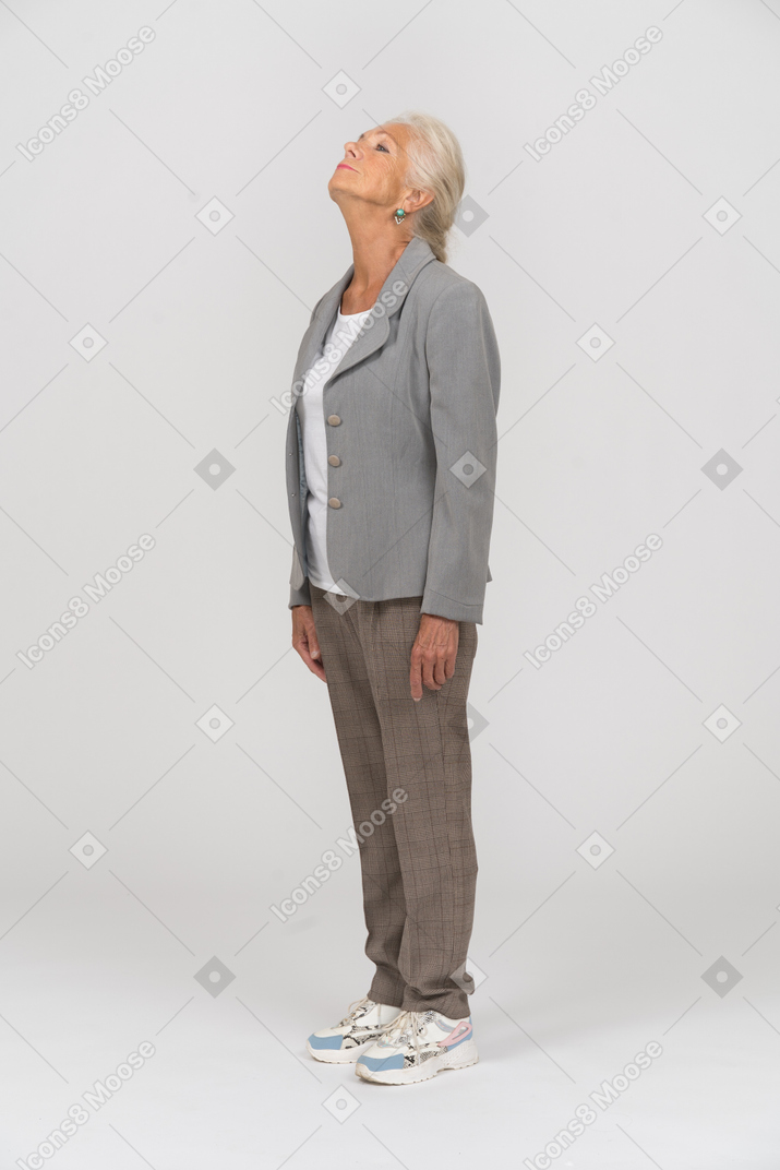 Vista laterale di una vecchia signora in giacca e cravatta che guarda in alto