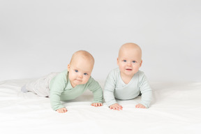 Любопытные дети близнецы лежат на животе