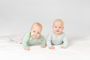 Curious babies twins lying on the stomach