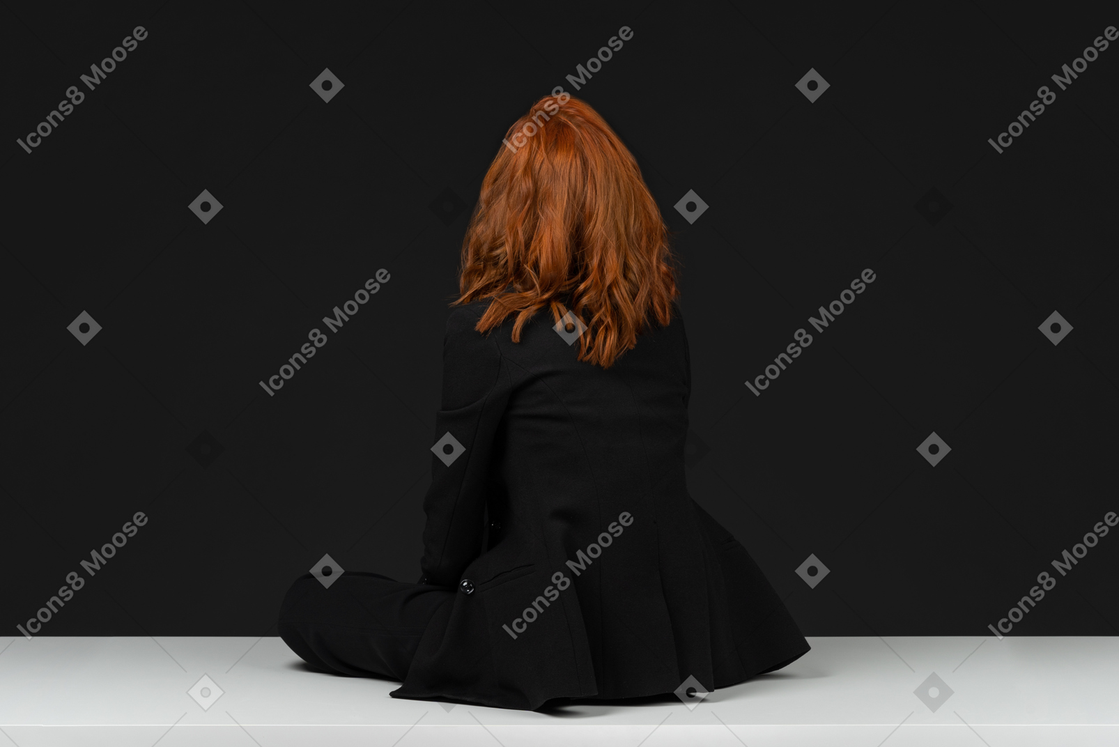 A back side view of the cute red haired woman sitting on the white table