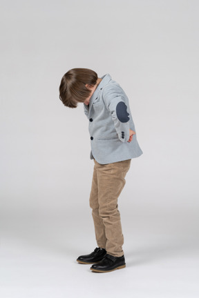 Little boy standing with his head down