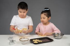 Маленькая девочка и ее брат пекут печенье