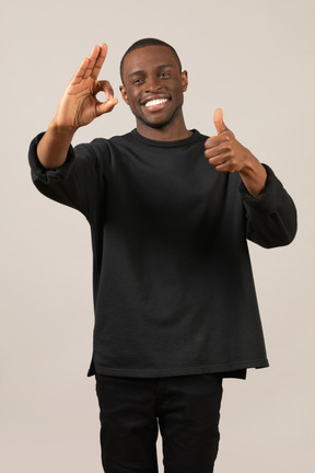 Smiling young man showing thumb up and ok sign