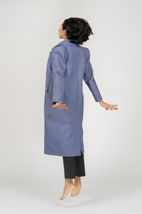Back view of woman in coat jumping