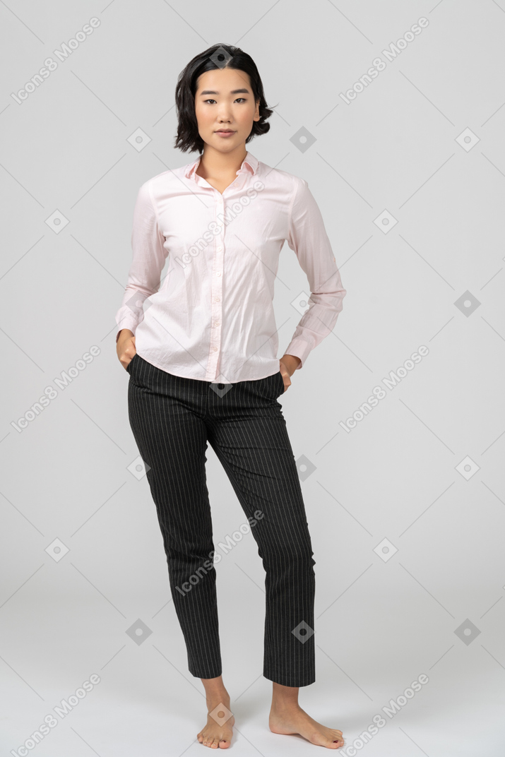 Женщина в офисной одежде стоит с руками на бедрах