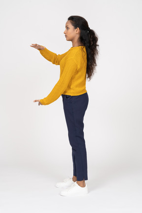 Vista lateral de una niña en ropa casual que muestra el tamaño de algo