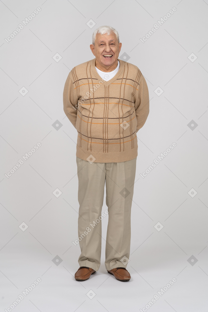 一个穿着休闲服的快乐老人的正面图，双手向后站着