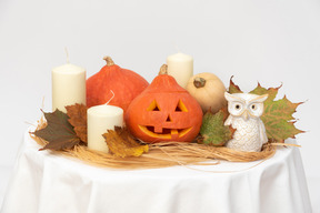 Calabazas talladas, hojas amarillas, velas y figura de búho.