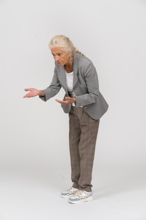 Side view of an old lady in suit bending down and explaining something